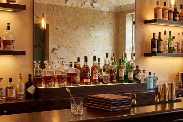 bar met antiek blanke spiegel aan de muur en daarvoor flessen